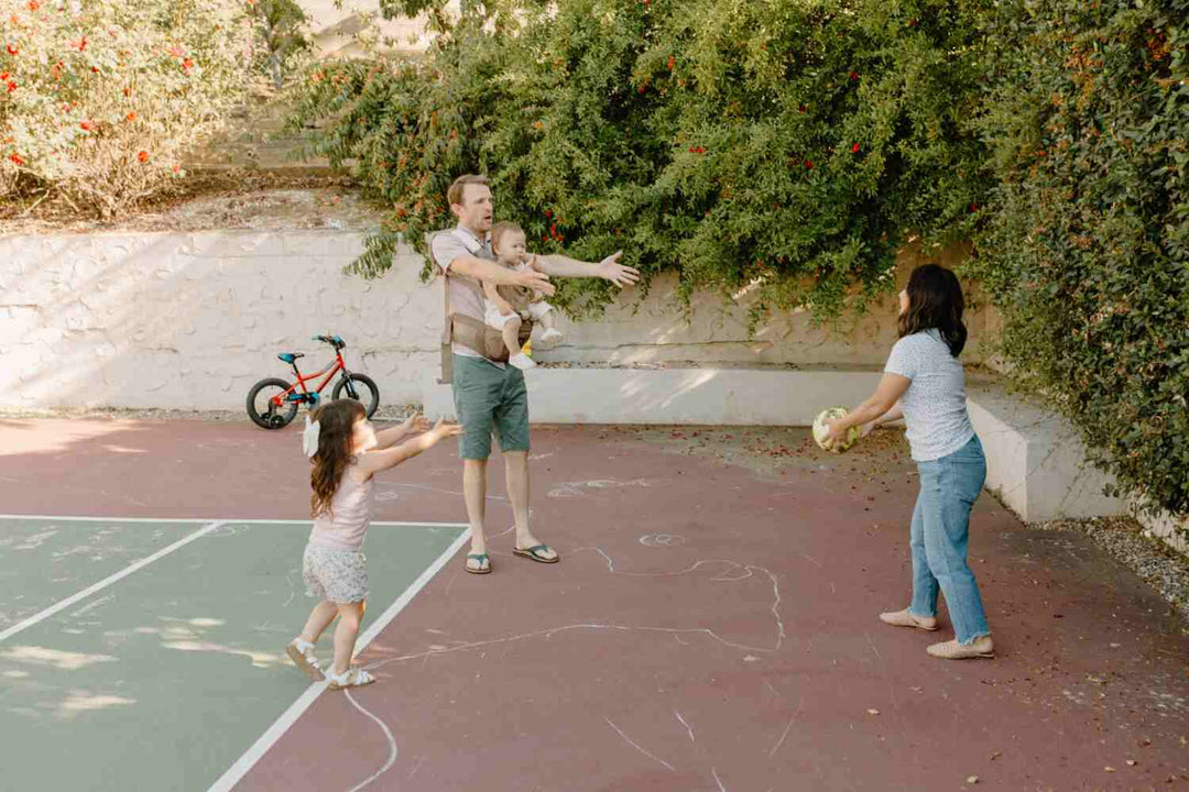 Mom and dad playing with children while using a baby carrier