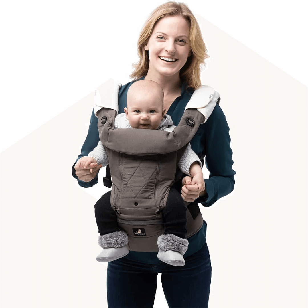 smiling woman carrying baby with huggs baby carrier
