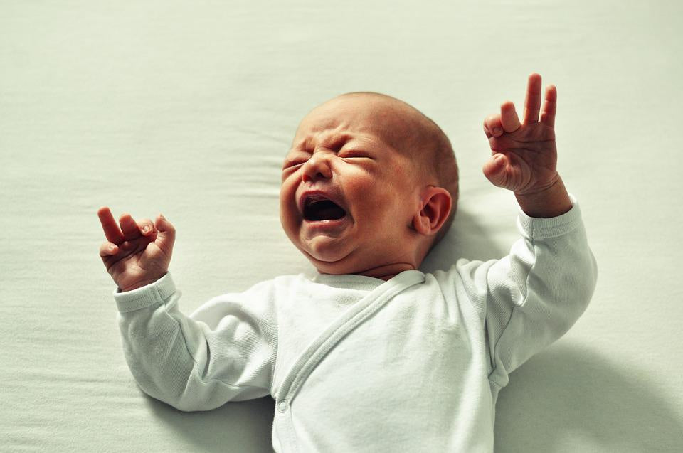 baby crying with hands in air