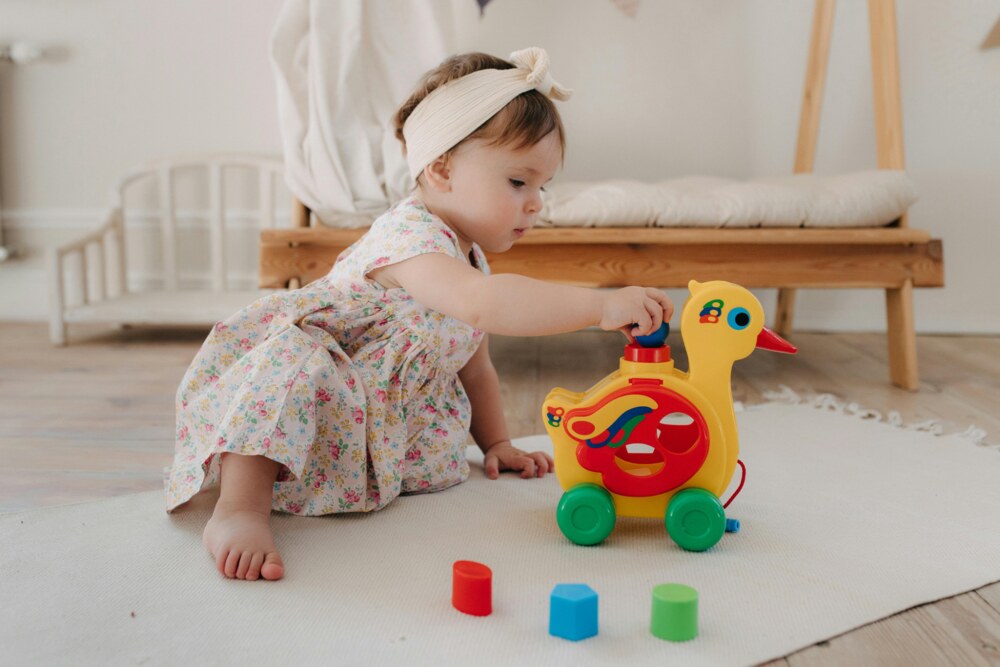 A baby girl playing with a toy duck during independent play