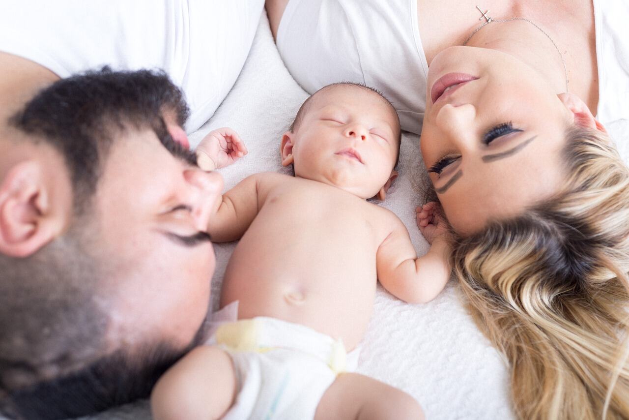 man and woman lying beside baby