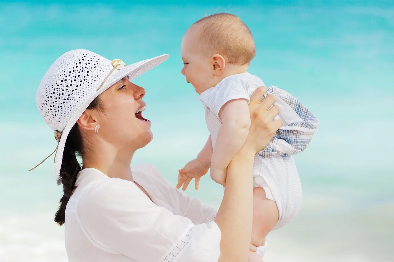 mom holding baby in sunshine near beach