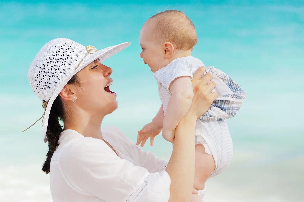 holding baby in sunshine near beach