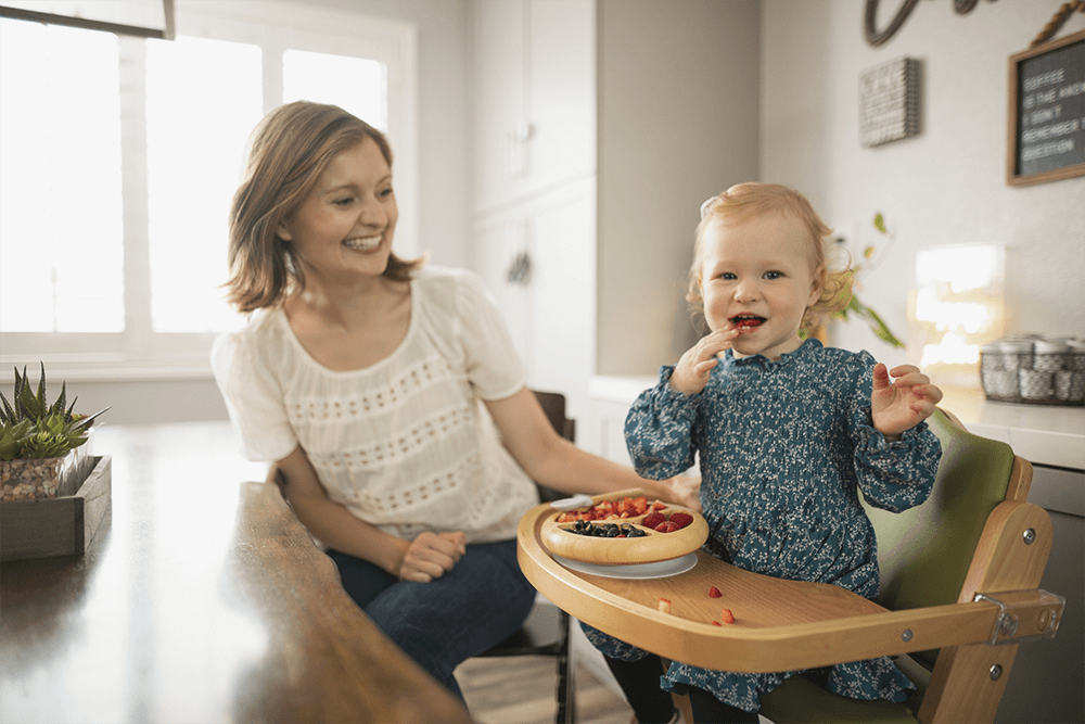 mom next to toddler eating from Bamboo Baby Suction Plate