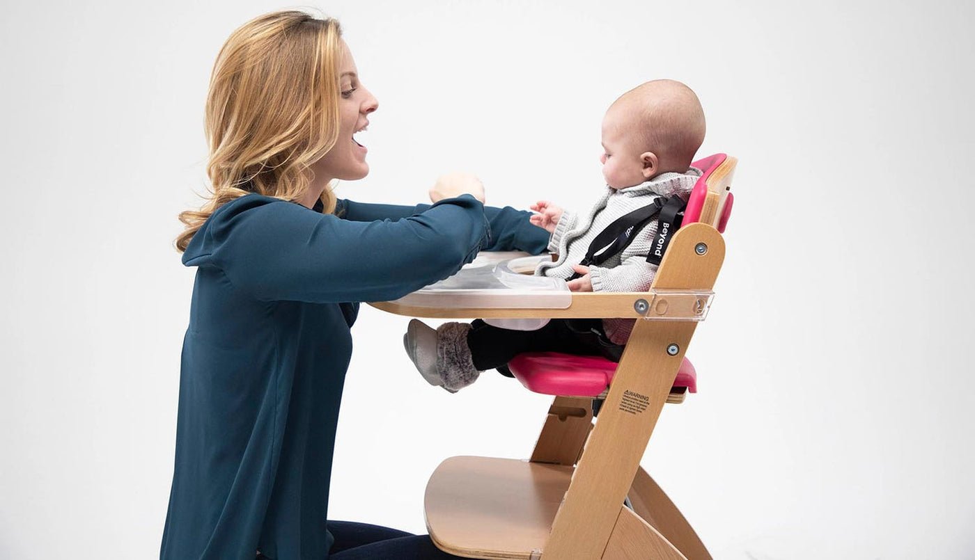 Parent crouching in front of baby in the adjustable modern Beyond Junior Y High Chair